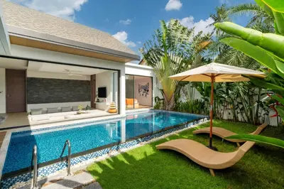 a swimming pool with an umbrella and chairs and a house at Sunny Day Dream Villa - Nai Yang Beach in Thalang