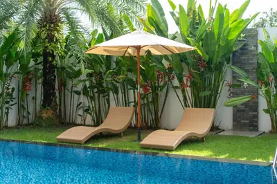 two chairs and an umbrella next to a pool at Sunny Day Dream Villa - Nai Yang Beach in Thalang