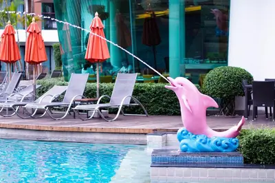a pink dolphin statue next to a swimming pool at The Beach Heights Resort SHA Plus in Kata Beach