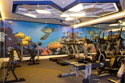 a gym with an aquarium themed room with tread machines at The Beach Heights Resort SHA Plus in Kata Beach