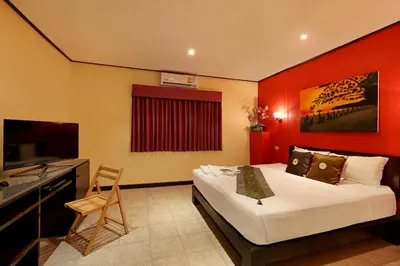 a bedroom with a bed with a red wall at Angus O'Tool's Guesthouse in Karon Beach