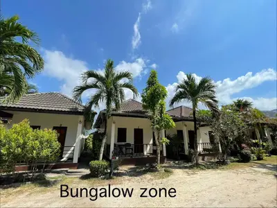 a house with palm trees in the yard at Ron Bungalow in Bang Tao Beach