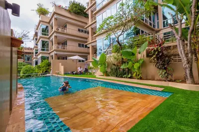 a woman swimming in a swimming pool in front of a building at Karon View Apartments in Karon Beach