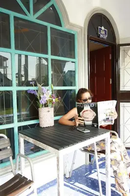 a woman sitting at a table reading a newspaper at Karon House 15B in Karon Beach