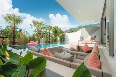 a living room with a couch and a swimming pool at Capucine Villas in Kamala Beach