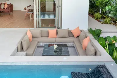 a living room with a couch next to a pool at Capucine Villas in Kamala Beach