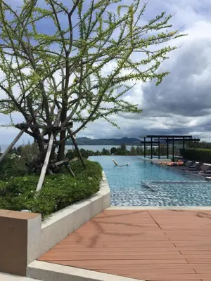 a pool with a tree and a person in the water at Phuket apartment surin beach in Thalang