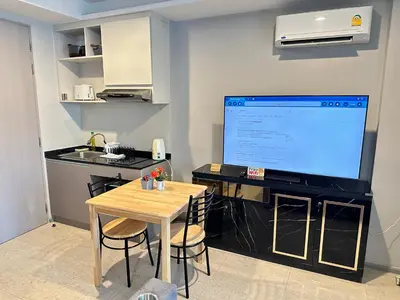 a kitchen with a table and a large screen television at Phuket apartment surin beach in Thalang