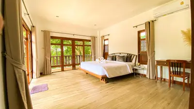 a bedroom with a bed and a wooden floor at Tropical garden in Phuket Town