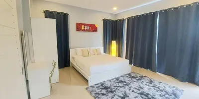 a bedroom with a bed with blue curtains and a rug at Udomsuk villa phuket in Bang Tao Beach