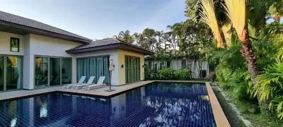 a swimming pool with two chairs next to a house at Beautiful villa walking distance from Bangtao Beach in Bang Tao Beach