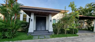 a house with a black door and some trees at Beautiful villa walking distance from Bangtao Beach in Bang Tao Beach