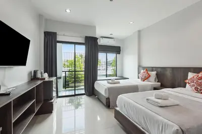 a hotel room with two beds and a flat screen tv at De Piraya residence in Mai Khao Beach
