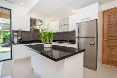 a kitchen with white cabinets and a stainless steel refrigerator at Anchan Villas Phuket - Private 2 Bedroom Pool Villas by Escape Villas in Bang Tao Beach