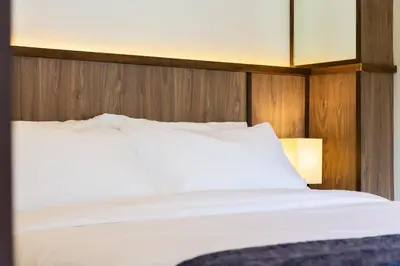 a bedroom with a white bed with a wooden headboard at Baan Kamana Guest House in Phangnga