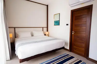 a bedroom with a bed and a wooden door at Baan Kamana Guest House in Phangnga