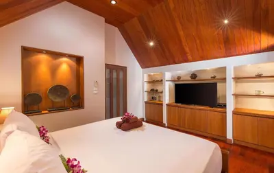 a bedroom with a large bed and a flat screen tv at Beachfront Kalim Beach Villa in Patong Beach