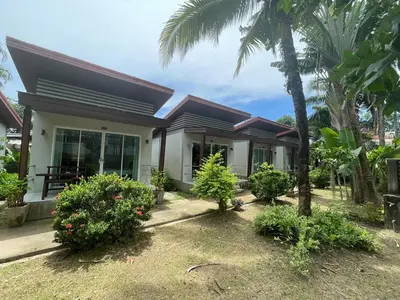 a house with a palm tree in front of it at Naiyang Boutique Resort in Ban Phak Chit
