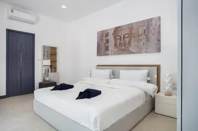 a large white bed with two blue pillows on it at Villa Elima. Lovely pool villa 2 bedrooms at Rawai in Rawai Beach