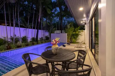 a table with chairs and a vase of flowers on a patio at Villa Elima. Lovely pool villa 2 bedrooms at Rawai in Rawai Beach