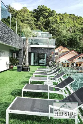 a row of lounge chairs in a yard with a building at Kata Hillside Hotel in Kata Beach