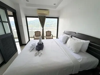 a bedroom with a large white bed with two chairs at Patong Tower apartment by Lofty in Patong Beach