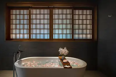 a bathroom with a bath tub with flowers in it at Noku Phuket in Chalong