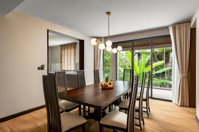 a dining room with a wooden table and chairs at Noku Phuket in Chalong
