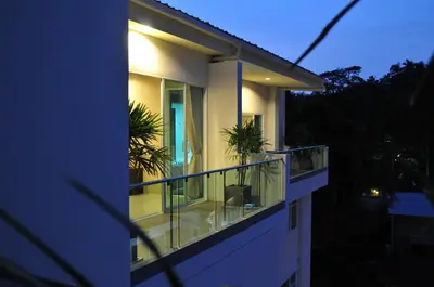 a house with a balcony with two plants on it at AM Surin Place in Surin Beach