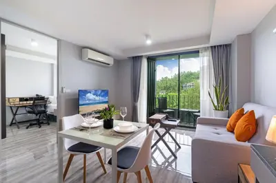 a living room with a couch and a table with chairs at Tropical Living Surin Beach Phuket in Surin Beach
