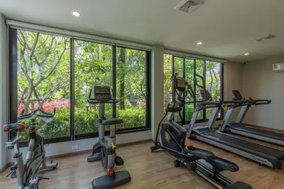 a gym with treadmills and elliptical machines and windows at Title Naiyang residence Excellent location with pool view in Nai Yang Beach
