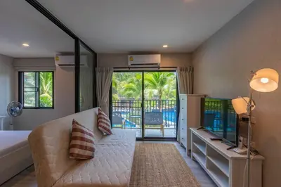 a bedroom with a couch and a tv and a balcony at Title Naiyang residence Excellent location with pool view in Nai Yang Beach