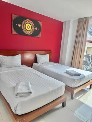 two beds in a room with a red wall at La Xenia Hotel Kata Beach in Kata Beach