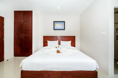a bedroom with a large white bed with flowers on it at The Topaz Residence Phuket Town in Phuket Town