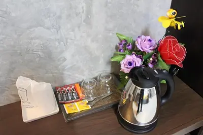 a table with a coffee pot and a bouquet of flowers at Beehive Phuket Old Town Hostel in Phuket Town