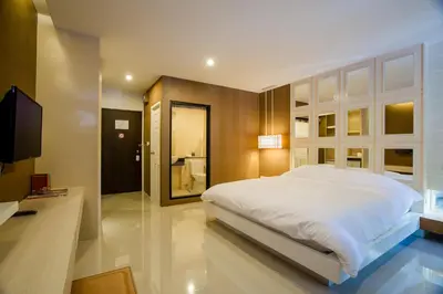 a bedroom with a large white bed and a television at Naka Residence in Phuket Town
