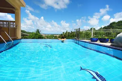a large swimming pool with blue water in a house at Luxury Four Bed Villa Jasmine, infinity pool, full staff , chef and breakfasts in Kata Beach