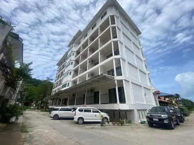 a white building with cars parked in front of it at Kata Place Hotel in Kata Beach