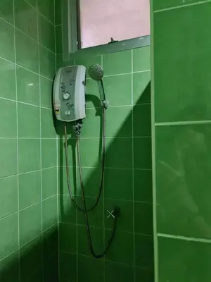 a green tiled shower with a blow dryer in a bathroom at ก้านกล้วยแมนชั่น Gankluy Mansion in Phuket Town