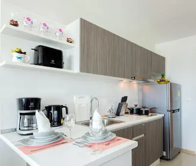 a kitchen with a counter with glasses and a refrigerator at Kata Beach OZONE Superb Fully Equipped studio kitchen washing machine air con in Kata Beach