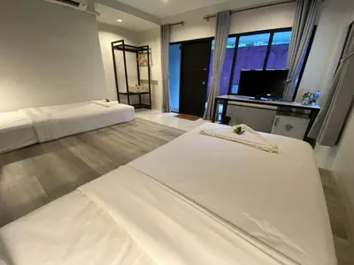 two beds in a room with a desk and a television at The dream garden in Ao Nang Beach