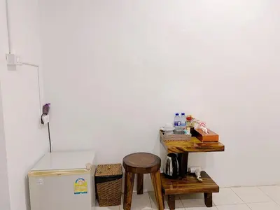 a kitchen with a table and a refrigerator and a stool at Remember at Phuket Town Hostel in Phuket Town