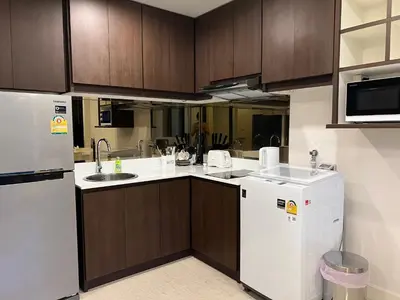 a kitchen with white appliances and wooden cabinets at The aristo-access pool room Surin beach in Phuket Town