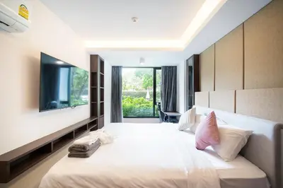a bedroom with a large white bed with a large window at The aristo-access pool room Surin beach in Phuket Town