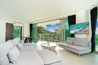 a living room with white furniture and large windows at Oceana Sea View - Kamala Beach in Kamala Beach