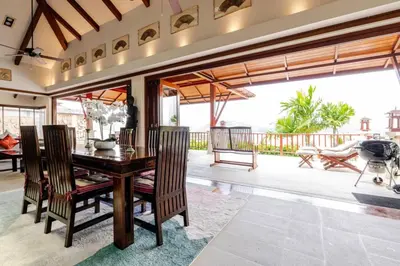 a dining room with a table and chairs and a balcony at Patong Seaview Luxury Villa Penda in Patong Beach