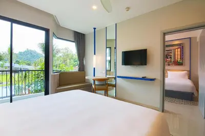 a bedroom with a bed and a tv and a balcony at Holiday Style Ao Nang Beach Resort, Krabi in Ao Nang Beach