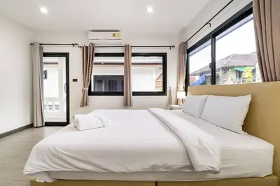 a large white bed in a room with windows at Kamala Fantasy 5 Bedroom Modern Private Pool Villa in Kamala Beach