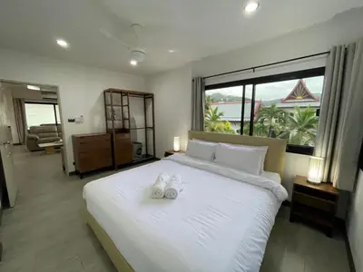 a bedroom with a large white bed with two shoes on it at Kamala Fantasy 5 Bedroom Modern Private Pool Villa in Kamala Beach
