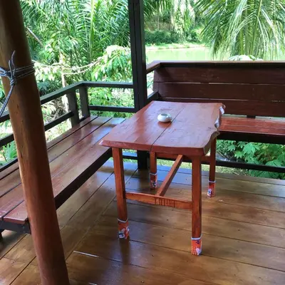 a wooden bench with a table on a porch at Lok Mun Bungalows in Ko Yao Noi